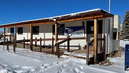  A snow-covered manufactured trailer with an entrance accessible via two steps or a ramp. 